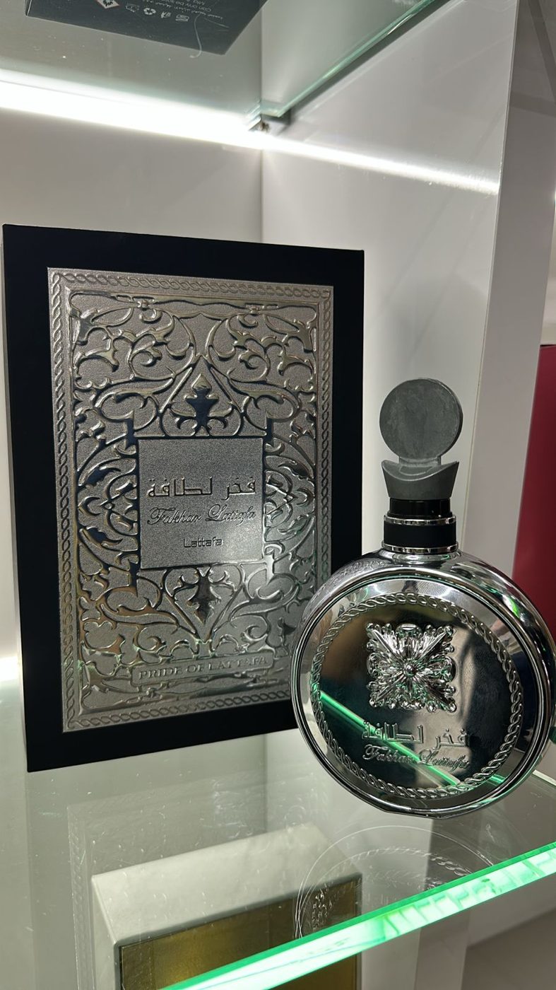 Perfume árabe em frasco prateado exposto ao lado de arte árabe emoldurada
