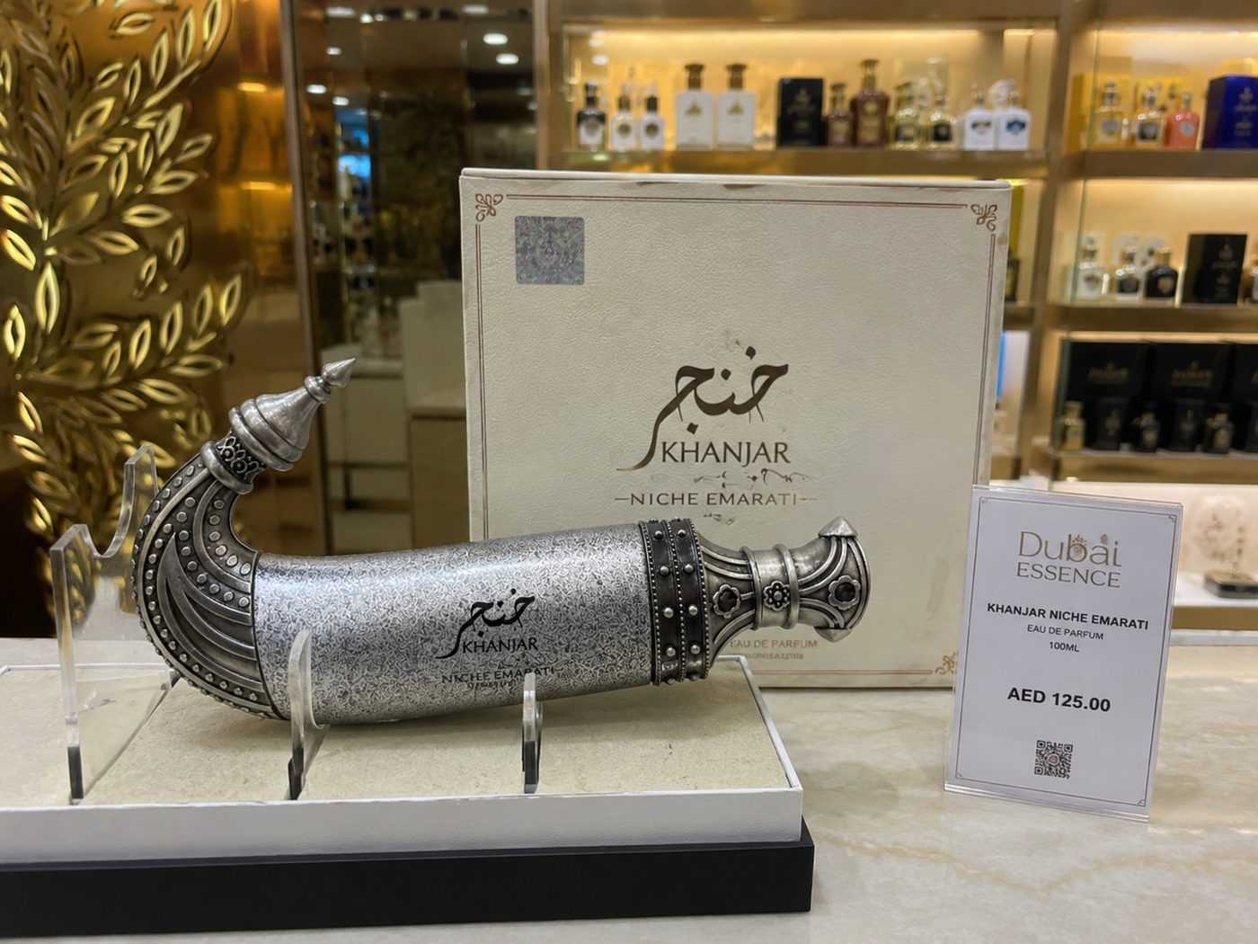Perfume árabe Khanjar em frasco prateado no formato de adaga sobre expositor